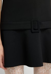 Schwarzes Kleid mit einem taillierten Oberteil und einem ausgestellten Rock, das eine glatte Textur aufweist und einen breiten Gürtel mit einer quadratischen Schnalle in der Taille hat.