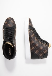 Wysokie sneakersy z czarną sztuczną skórą, złotymi akcentami i brązowym wzorem monogramu, z białą podeszwą i sznurowanym zapięciem.