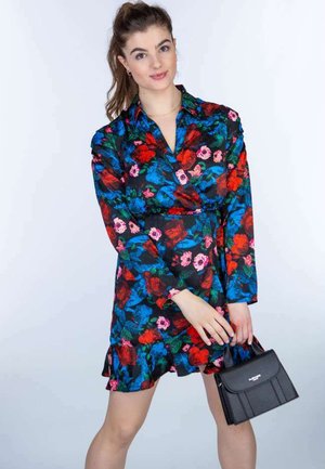 Blomsterwrapkjole med lange ærmer, sort bund, røde og blå blomster, flæset kant. Sort håndtaske med topgreb og hvidt logo detaljer.