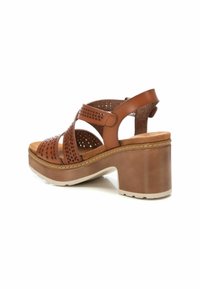 Las sandalias de tacón de cuero marrón cuentan con un diseño perforado, una correa trasera ajustable y un tacón de plataforma grueso con una suela texturizada.