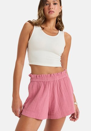 White ribbed crop top paired with light pink, textured, high-waisted shorts featuring a ruffled waistband and relaxed fit.