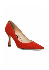 Zapato de tacón alto de ante rojo con punta afilada y tacón stiletto delgado. El forro interior es beige. Presenta un detalle de suela negra.