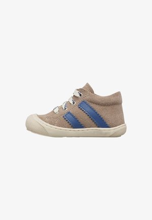 Zapatilla de ante beige para niño pequeño con tiras de cuero azul en zigzag, suela blanca, puntera texturizada y cordones blancos con acentos azules.