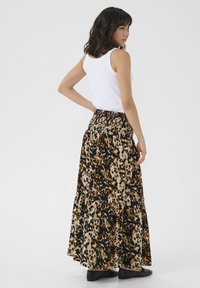 Jupe maxi avec un imprimé léopard dans des nuances de marron, noir et beige. Fabriquée en tissu léger avec une taille froncée et un design à volants.