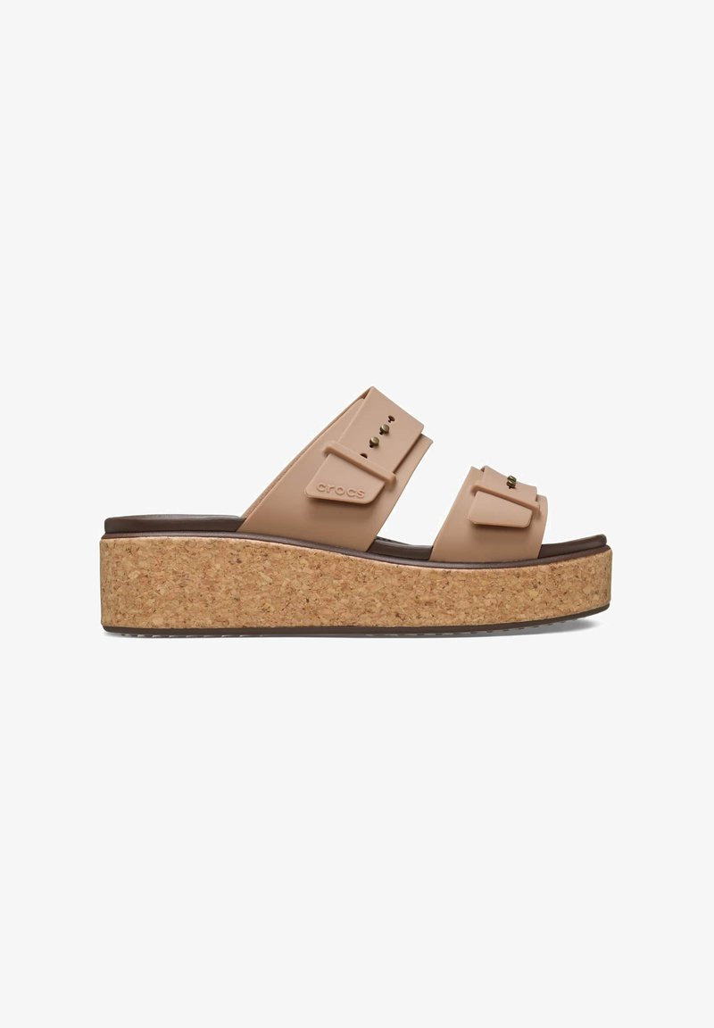 Korkplattform-Sandalen mit zwei breiten, beigen Riemen, die ein erhabenes Muster und Messingakzente aufweisen, und zusätzlichen Halt sowie Höhe bieten.