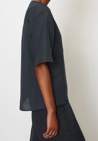 Tmavě šedý lněný top s krátkými rukávy, volným střihem, kulatým výstřihem a bočními rozparky, nabízí lehký a prodyšný design.