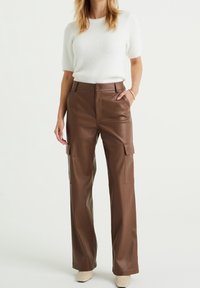 Bruna lädercargo-byxor med rak passform, framfickor och sidofickor. Matchas med en vit strukturerad stickad tröja.