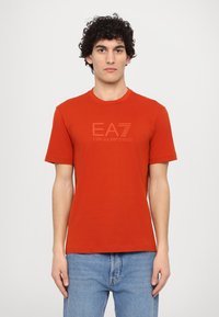 Red cotton t-shirt with short sleeves, round neck, featuring a subtle EA7 Emporio Armani logo in a tonal print at the front.