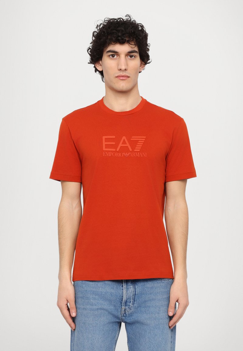 Red cotton t-shirt with short sleeves, round neck, featuring a subtle EA7 Emporio Armani logo in a tonal print at the front.
