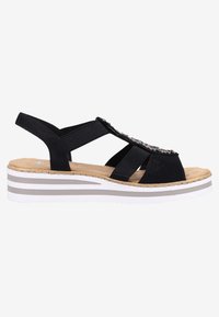 Sandale noire avec des bandages élastiques et des détails embellis, dotée d'une semelle compensée avec une semelle intérieure marron clair et une semelle intermédiaire rayée blanc-gris.