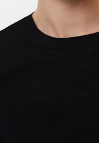 Zwarte gebreide trui met een ronde hals en geribbelde structuur. Soepele stof met een subtiele glans, nauwsluitend ontwerp.