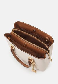 Beżowa skórzana torba na ramię z brązową podszewką, dwoma zamykanymi na suwak przegrodami, złotymi elementami oraz pojedynczym paskiem. Charakteryzuje się gładką teksturą i solidną konstrukcją.