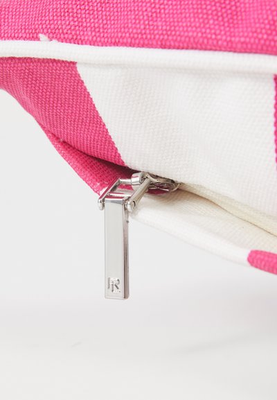 Pochette zippée rayée rose et blanche, faite d'un tissu texturé, avec un tirette en métal argenté et une étiquette rectangulaire.