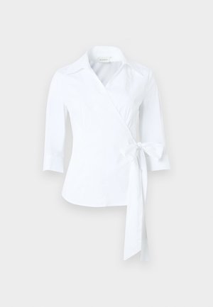 White wrap blouse with three-quarter sleeves, pointed collar, and tied waist bow on the right side against a neutral background.