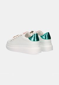 Zapatillas blancas con un cuerpo de cuero suave, ojales metálicos dorados y acentos de estampado de serpiente verde brillante en el talón. Suela de goma blanca gruesa.
