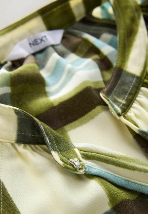 Zaļa un zila pleda raksta krekla audums ar gludu tekstūru. Aprīkots ar apaļu apkakli un sudraba aizdari. Etikete saka "NEXT".