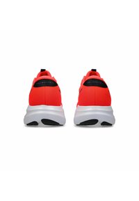 Baskets de course rouges avec un dessus texturé, semelle blanche et accent noir au talon. Comprend une étiquette garantissant confort et performance.