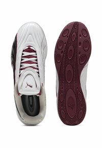 Hvide og kastanjebrun sneakers med en tekstureret læderoverdel, buet design og en mønstret gummisål med ovale former for trækkraft.