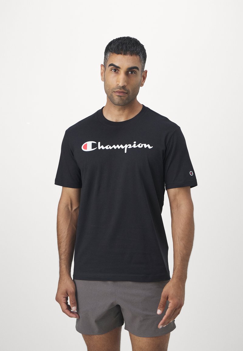 Schwarzes Baumwoll-T-Shirt mit einem weißen, geschwungenen "Champion"-Logo und roten Akzenten. Kurze Ärmel und klassischer Rundhalsausschnitt.