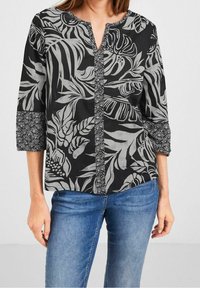 Blusa nera con motivo di foglie tropicali grigie, scollatura a V, maniche a 3/4 e bordo testurizzato lungo la parte anteriore e i polsini delle maniche.