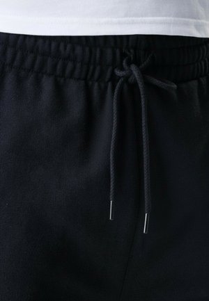 Pantaloni della tuta neri con vita con coulisse e terminali in metallo, tessuto liscio e fascia elastica per il massimo comfort.