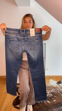 Jeans de corte recto en azul, con un parche de cuero en la cintura, dos bolsillos traseros y un ligero desvanecimiento en la tela.