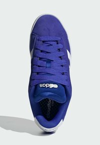 Sneaker in suede viola con dettagli bianchi, linguetta testurizzata e lacci. Presenta una soletta imbottita e un marchio sul lato e sulla linguetta.