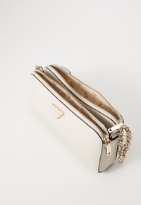 Biała skórzana torebka na ramię z dwiema zamykanymi na zamek komorami, złotą hardware i teksturowanym paskiem w formie łańcucha. Wnętrze wykończone jest wzorzystą podszewką.