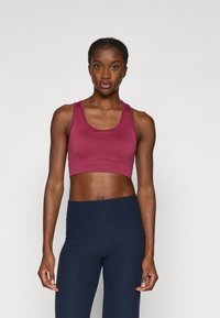 Burgundy cropped tank top dengan tali lebar dipadukan dengan legging bergaris navy. Tekstur halus dengan desain yang pas, cocok untuk pakaian aktif.