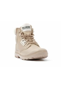 Botas de tobillo beige con un acabado de cuero liso, puntera redondeada, suela de goma y forro de piel sintética alrededor del tobillo. Logo en la lengüeta.