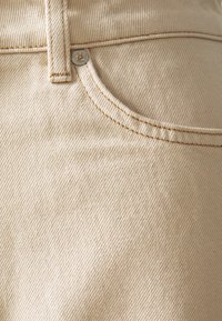Beige džíny z denimu s texturovaným povrchem, se snadno zapínatelným kovovým knoflíkem a prošitím na kapsách a pase.