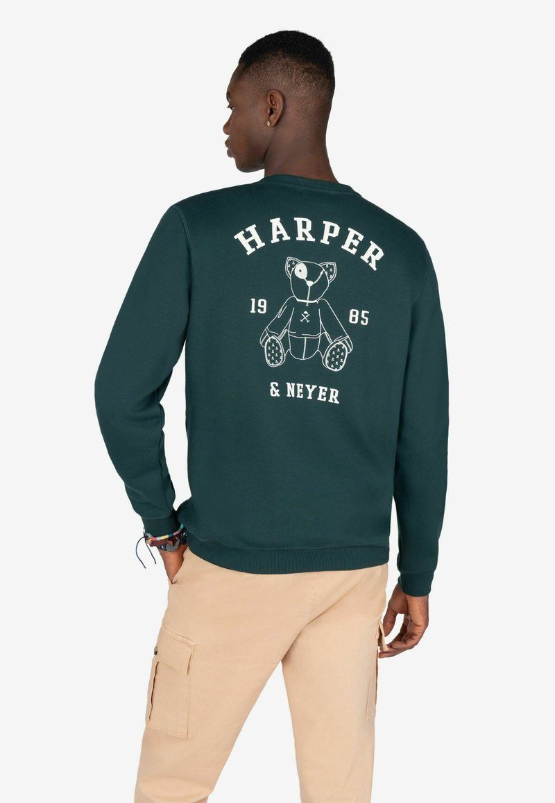 Sudadera verde de cuello redondo con un gráfico de oso de peluche en la parte posterior, junto con el texto "HARPER 1985 & NEYER" en blanco. Tejido suave con puños acanalados.