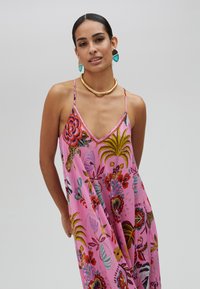 Robe rose à motif floral avec un col en V et des bretelles spaghetti, ornée de broderies colorées et d'accents en perles, fabriquée en tissu léger.