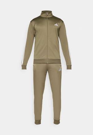 Survêtement de sport vert olive en matériau lisse avec un col haut, une fermeture éclair à l'avant, et des bandes blanches sur la veste et le pantalon.