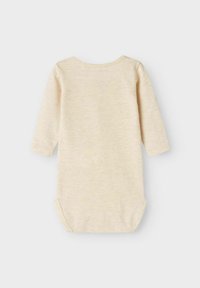 Bodysuit pour bébé à manches longues en tissu beige clair et doux avec une texture subtile. Il présente un col rond et des pressions en bas.