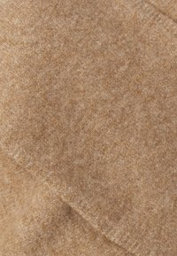 Μαλακό, ανοιχτό καφέ μαλλί με λείο υφή. Παρουσιάζει υποδειγματικές παραλλαγές σε απόχρωση και μια ελαφριά γυαλάδα, κατάλληλο για ρούχα ή αξεσουάρ.