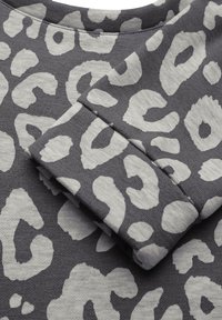Tessuto grigio con stampa leopardata in grigio chiaro. Il design presenta forme irregolari e una finitura morbida, leggermente texture.