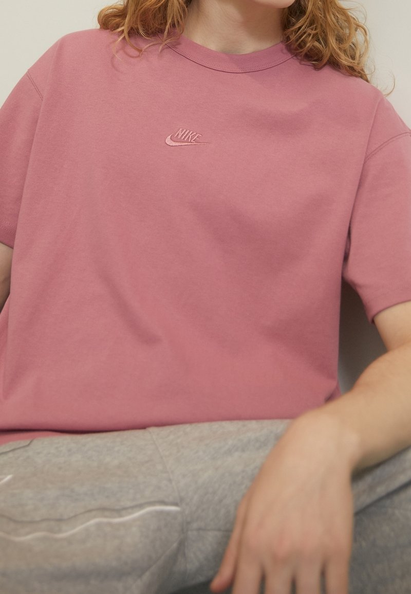 Rosa bomullströja med avslappnad passform, med en broderad Nike-logotyp på bröstet. Korta ärmar och rund halsringning.