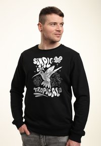 Sort sweatshirt med lange ærmer, der har et grafikdesign af en kolibri og tropiske blade i hvid og lys grå.