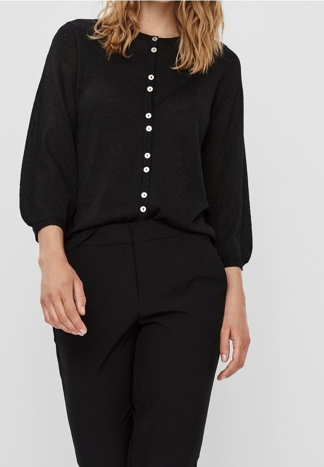 Blusa nera in maglia con maniche lunghe, caratterizzata da una chiusura frontale con bottoni e bottoni bianchi. Il tessuto ha una leggera lucentezza e un fit rilassato.