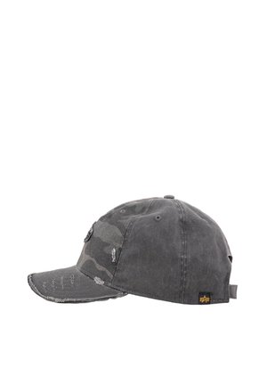 Worn black baseball cap with distressed details, camouflage pattern on front panel, and small black tag with yellow logo at side.