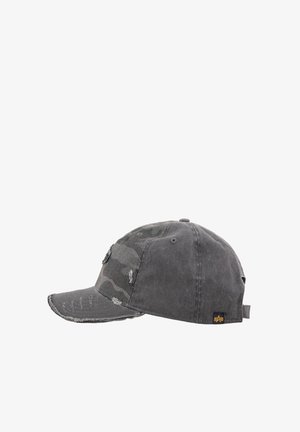 Worn black baseball cap with distressed details, camouflage pattern on front panel, and small black tag with yellow logo at side.