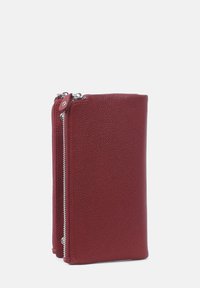 Röd läderplånbok med en texturerad yta, som har en dragkedjestängning och silverfärgade detaljer. Kompakt rektangulär form.