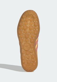 Soletta in gomma per sneaker con un prominente motivo ondulato, grip circolari e una finitura color miele. Presenta un design del logo centrale.