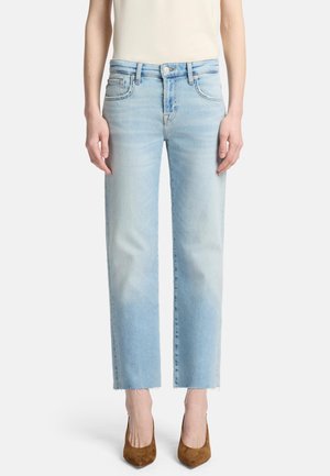Lichtblauwe denim jeans met een rechte snit, onafgewerkte zoom en vijf zakken; gedragen met een beige top en bruine hakken.