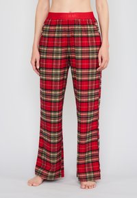 Punainen ruudullinen aamutakkihousut, joissa on leveä lahje, musta ja beige tarkkuuskuvio sekä joustava vyötärö, jossa on kaiverrettu teksti "DOOPJEANS".