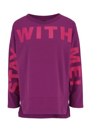 Lila Langarm-Sweatshirt mit großer pinker Schrift "BLEIB BEI MIR!" auf der Vorderseite und dem rechten Arm. Weicher Stoff mit lockerer Passform.