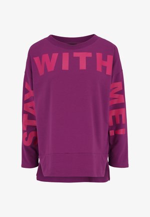 Lila Langarm-Sweatshirt mit großer pinker Schrift "BLEIB BEI MIR!" auf der Vorderseite und dem rechten Arm. Weicher Stoff mit lockerer Passform.