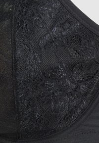 Soutien-gorge in pizzo nero con motivo floreale testurizzato; presenta una banda liscia, bordi senza cuciture e tessuto morbido per il comfort.