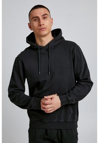 Melnas kapuces džemperis izgatavots no mīkstas auduma, ar kangarū dzēlienu, rāvēja kapuci, ribinātām piedurknēm un apakšmalu, ar smalkiem šuvumu akcentiem.